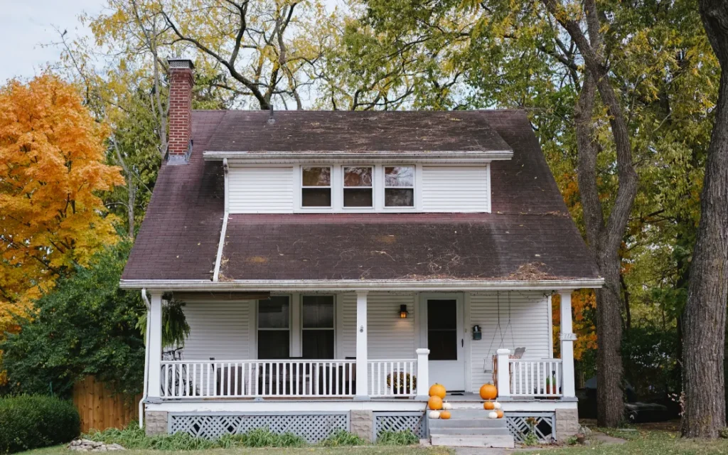 White two-story home with a front porch and fall trees in Wisconsin